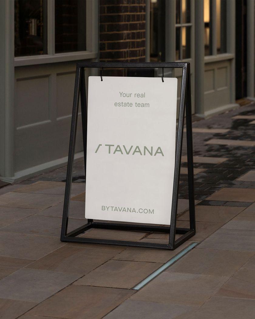 A white standing sign with "This is your real, estate team" written on the centre top, the logo "By Tavana" in the middle centre, and a URL on the centre bottom of the design.