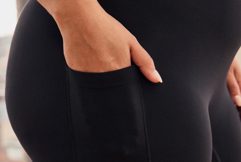 A close up of a woman placing her hand inside of a black slip short pocket